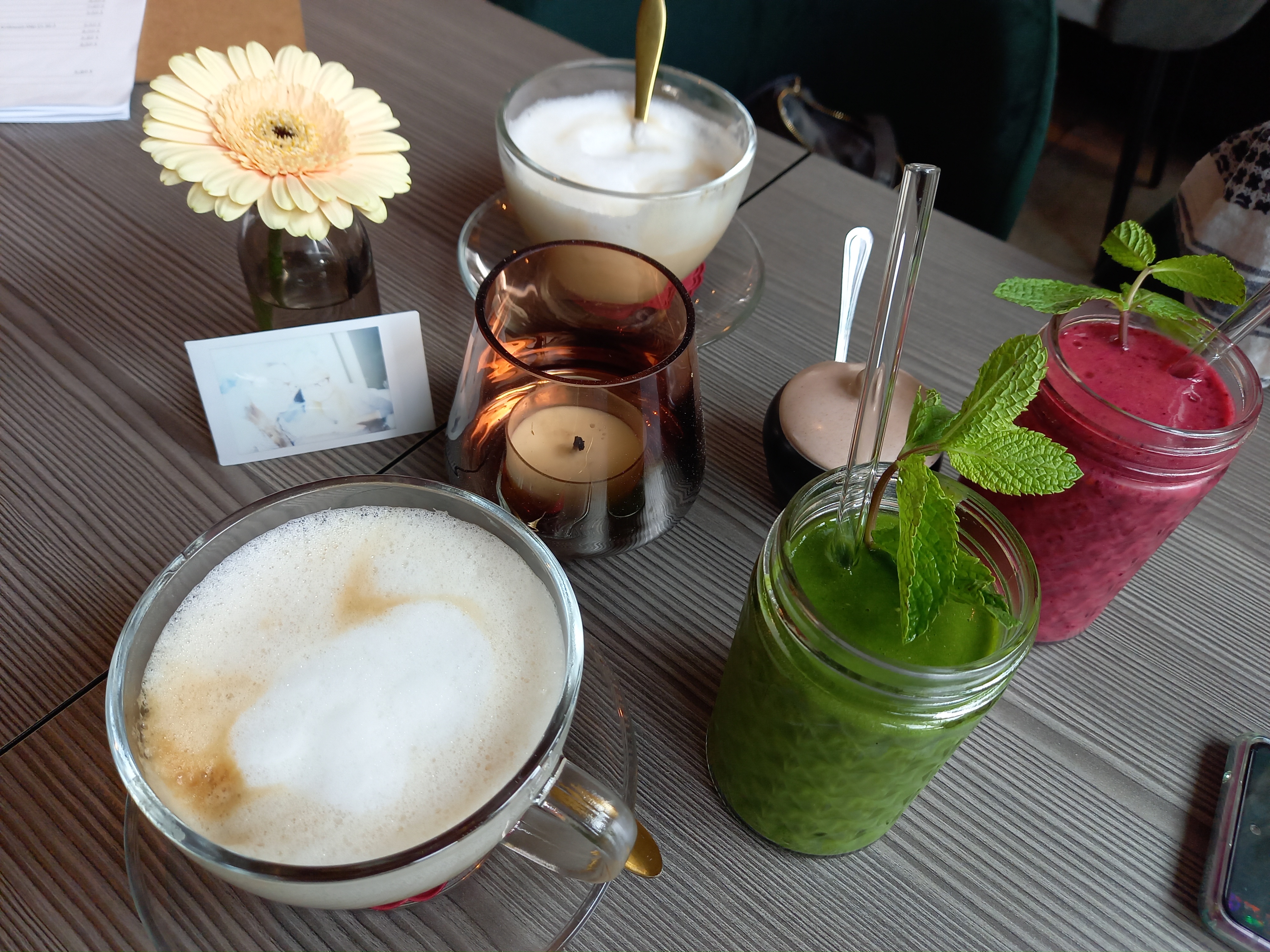 Auf einem Tisch stehen verschiedene Getränke sowie eine Blume und eine Kerze zur Dekoration. Dies ist ein Symbolbild für touristische Betriebe.